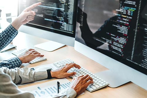 colleagues looking over code on computer